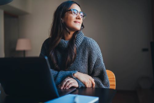 Woman sitting with laptop, looking away