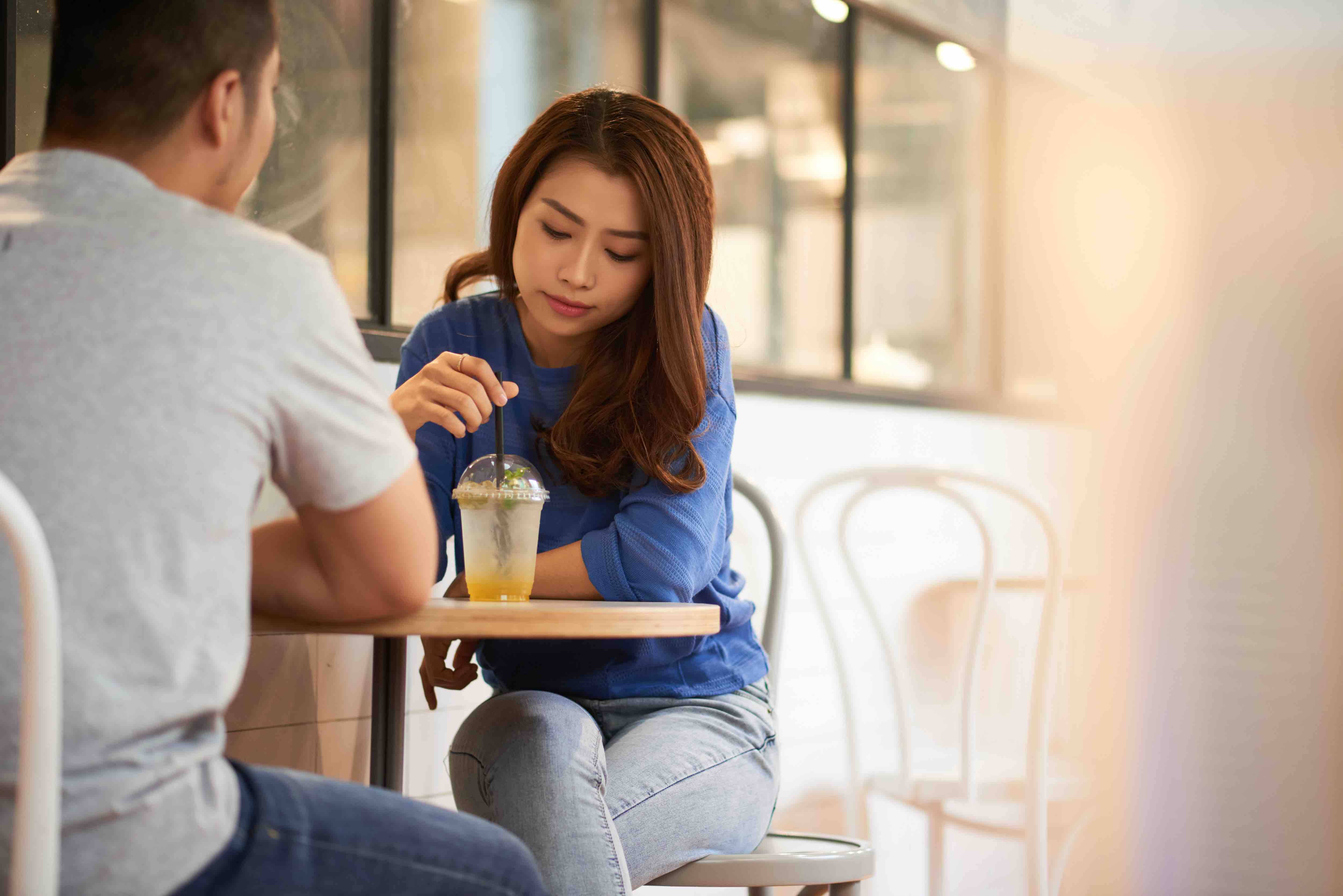 woman in a conversation at a coffee shop, looking bored