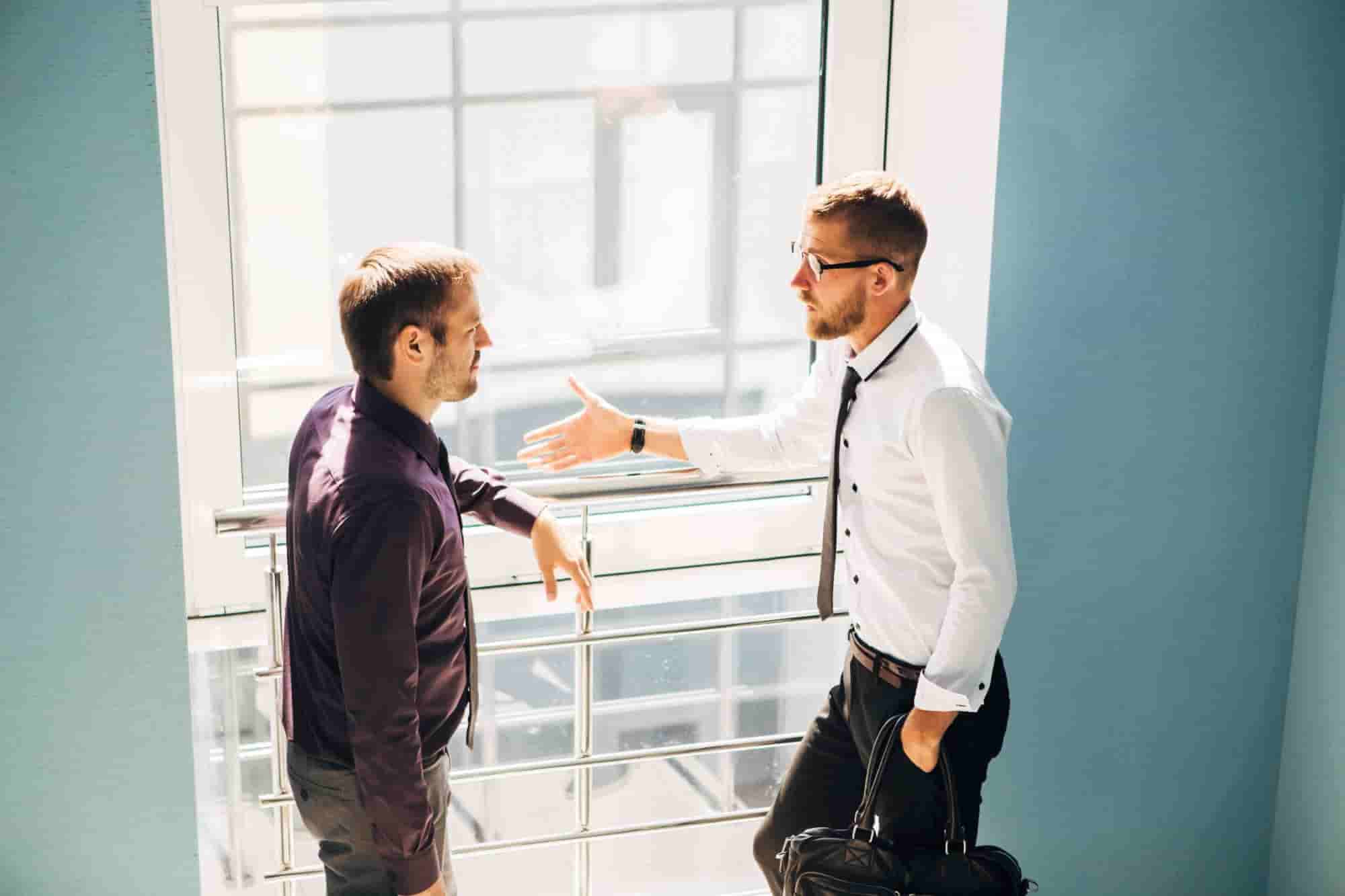 Two men having a conversation in the hallway at work