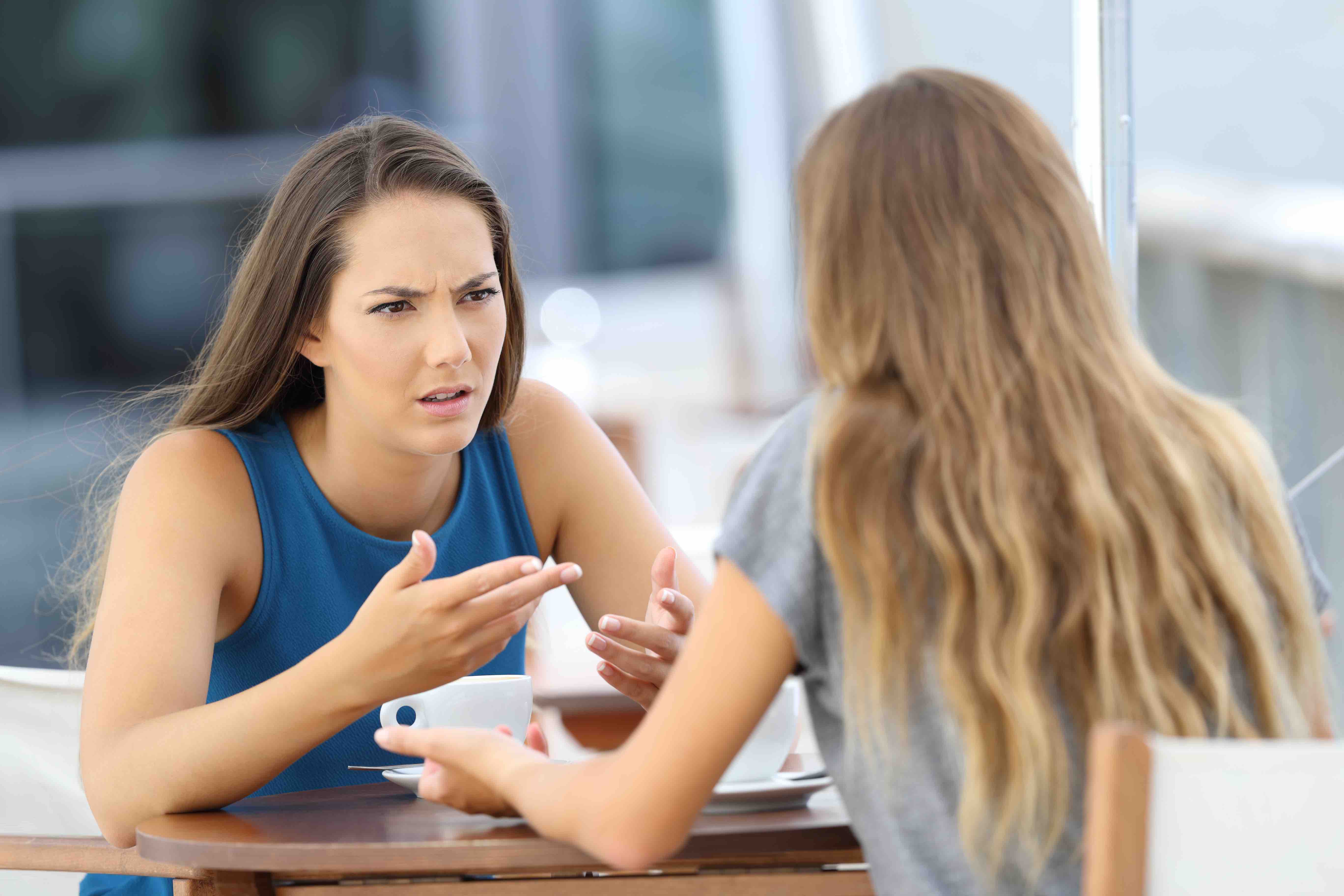 Two women sitting at a table having a heated conversation
