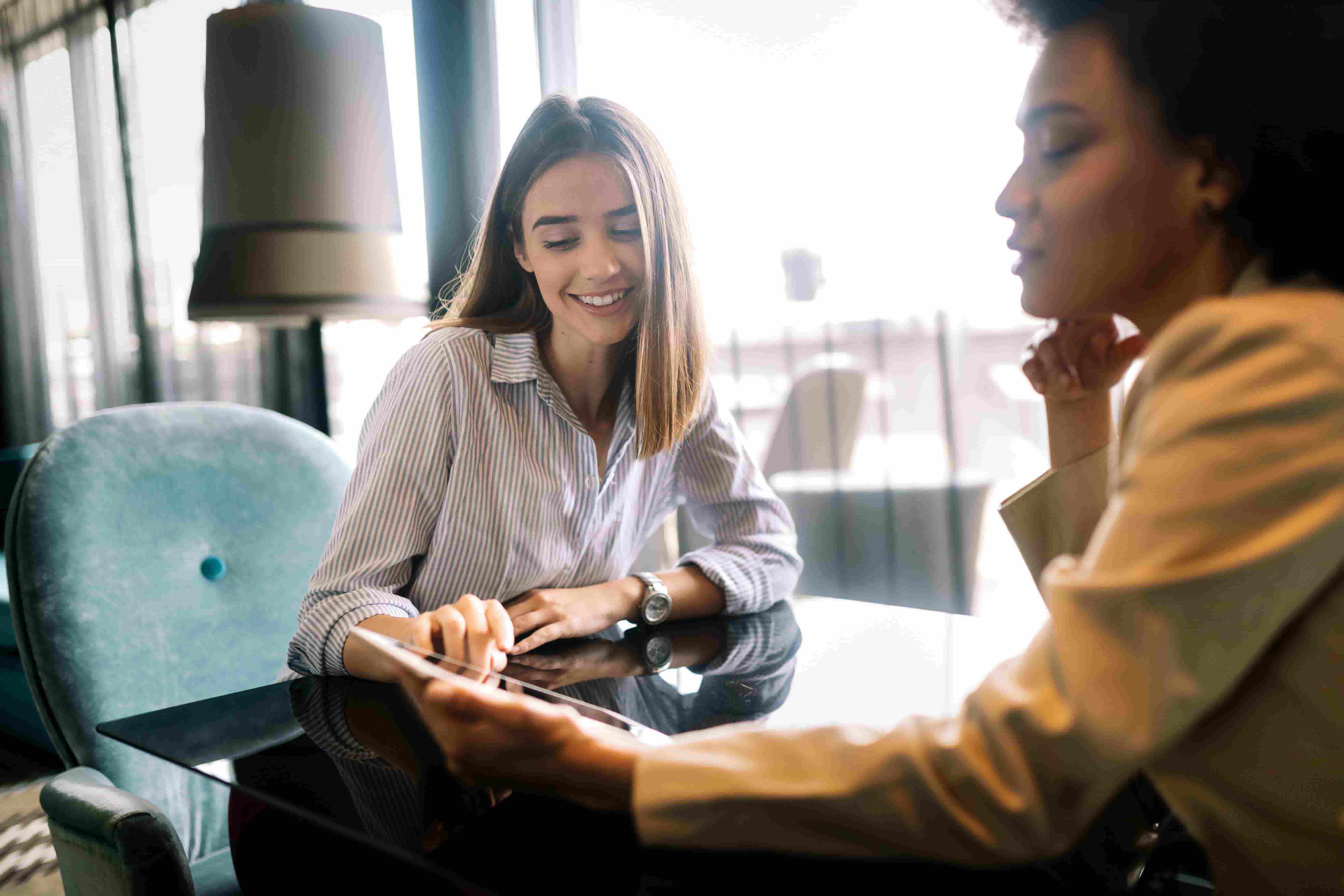 Two women looking at a computer tablet to find peer coaches